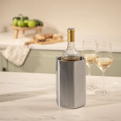 Vacu Vin Hive – охладител за вино от неръждаема стомана с гел елемент, поставен върху маса до две чаши бяло вино.